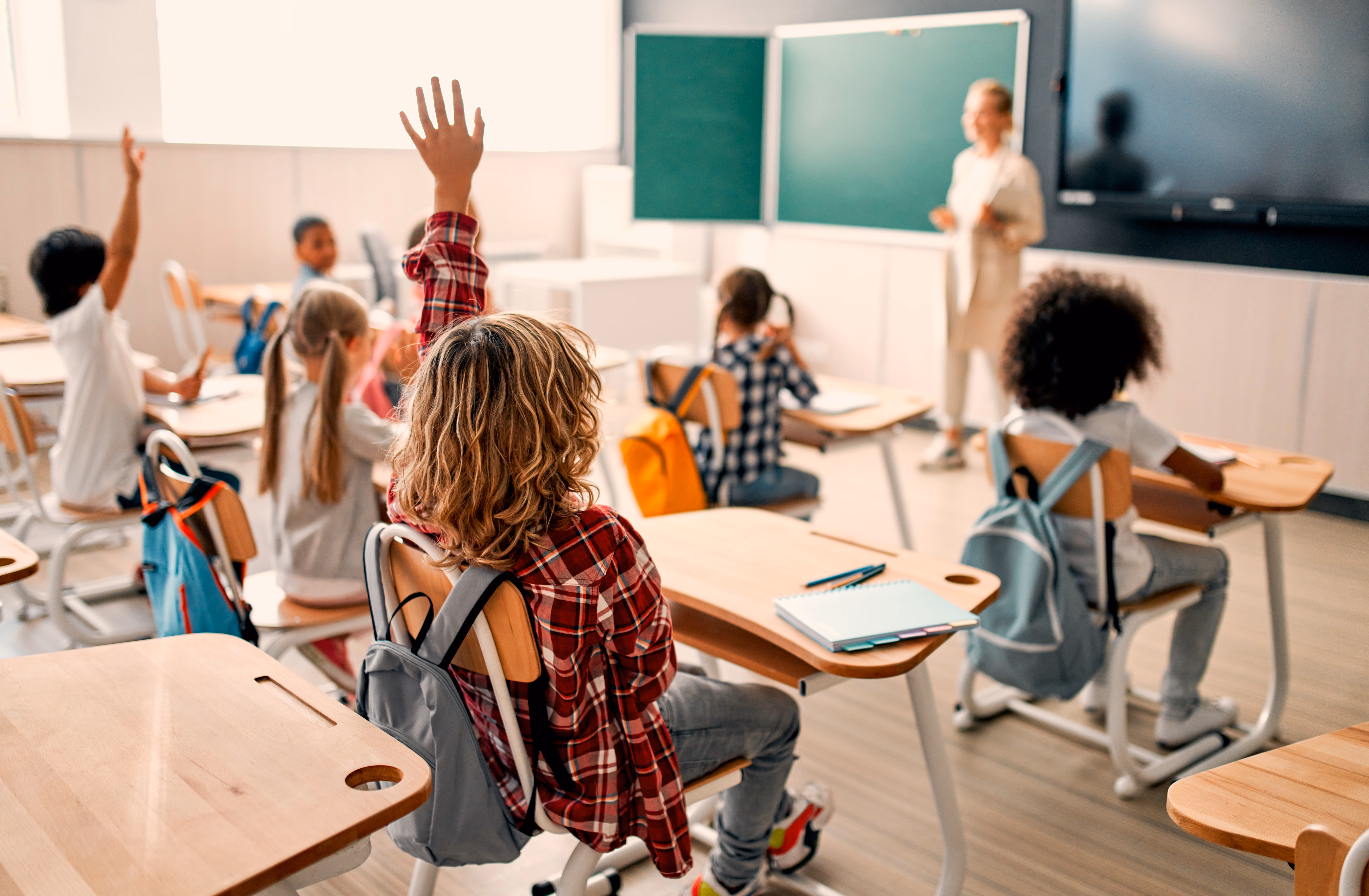 Students in a classroom with hands raised